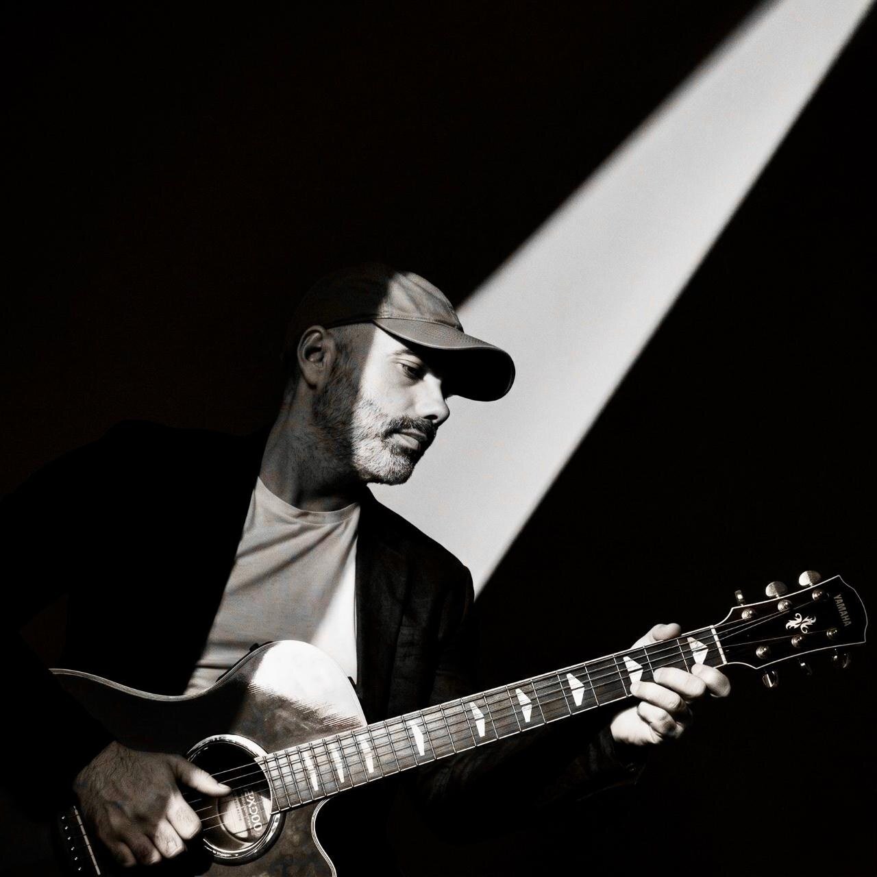 Zambayonny con guitarra bajo un haz de luz
